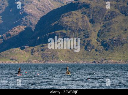 Elgol, Isle of Skye, Schottland. Paddleboarder und Hund mit Cullins im Hintergrund Stockfoto