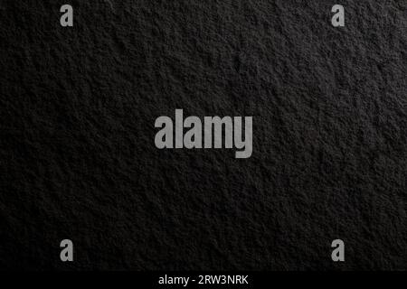 Nahaufnahme einer dunkelgrauen, fast schwarzen Oberfläche aus massivem Granit, Vorderansicht. Abstrakter natürlicher texturierter Hintergrund in Schwarzweiß, Kopierraum Stockfoto
