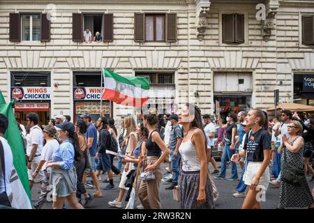Rom, Italien. September 2023. 16. September 2023, Rom, Italien: Zwei Zuschauer beobachten aus dem Fenster Frauen, die gegen das iranische Regime um die iranische Flagge während der Demonstration zum Gedenken an den Tod von Mahsa Amini in Rom protestieren. Mahsa Amini wurde am 13. September 2022 von der religiösen Polizei in Teheran verhaftet, weil das Gesetz über die obligatorische Verhüllung nicht eingehalten wurde. Sie starb unter verdächtigen Umständen nach drei Tagen im Koma am 16. September 2022 im Alter von 22 Jahren. Quelle: ZUMA Press, Inc./Alamy Live News Stockfoto