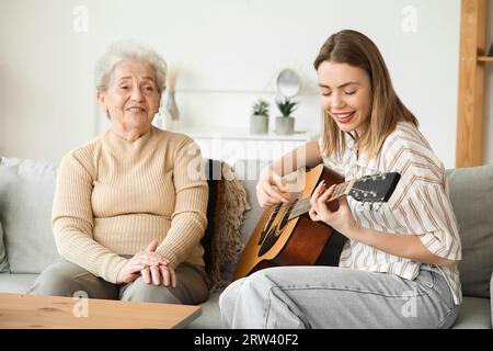 Ältere Frau und ihre Enkelin spielen zu Hause Gitarre Stockfoto