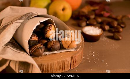 Gebratene Kastanien in einer Papiermembran, auf eine rustikale Küche Arbeitsplatte. Stockfoto