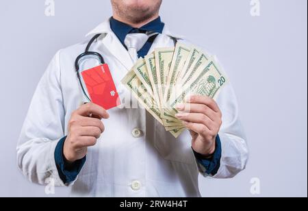 Arzthände, die Kreditkarte und Geld isoliert halten. Nicht erkennbarer Arzt, der Geld und Kreditkarten isoliert hält Stockfoto