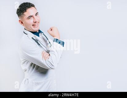 Arzt zeigt Muskeln und lächelt isoliert. Junger Arzt, der Kraft mit seinem Arm zeigt Stockfoto