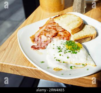 Englisches Frühstück mit Speck, Toast und Eiern, serviert in einem Café in London Stockfoto