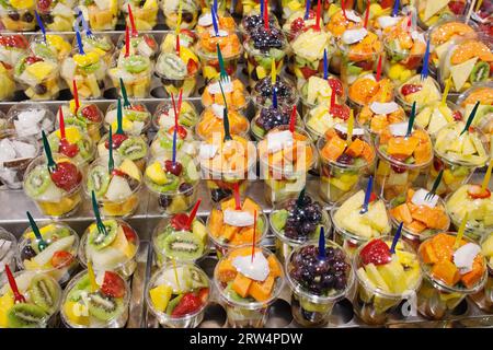 Frische, geschnittene, geschälte Mischung von Früchten verschiedener Art in Behältern mit Gabeln auf einem Marktstand, gesunde Ernährung nahrhaftes Streetfood, hoher Vitamin Stockfoto