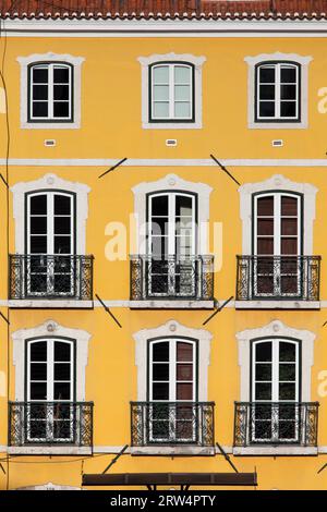 Traditionelles Gebäude mit gelber Fassade und hohen Fenstern mit Balkonen in Lissabon, Portugal Stockfoto