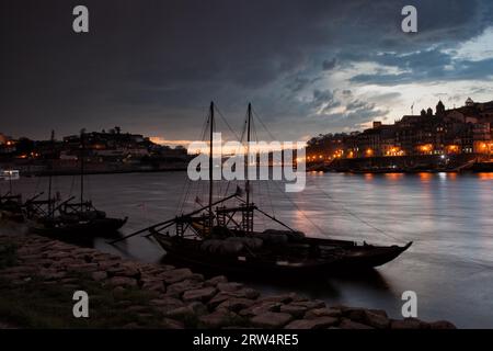 Stürmischer Abendhimmel über den Städten Porto und Vila Nova de Gaia in Portugal, Rabelo Boote auf dem Fluss Douro Stockfoto