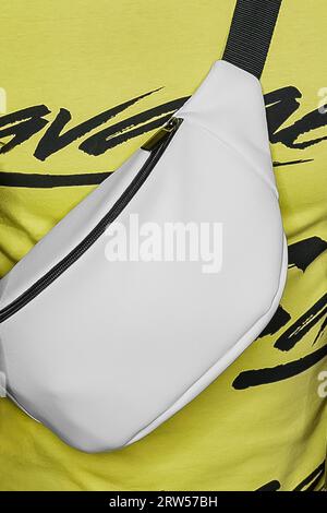 Nahaufnahme weiß, abstrakt, Taille oder Schultertasche, Objekt, Attribut von Stil und Mode auf einem hellen gelben Hintergrund. Stockfoto