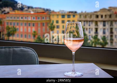 Ein Glas provenzalischer Roséwein in einer Bar auf dem Dach über der Altstadt Vieille Ville mit verschwommenen Gebäuden im Hintergrund, Nizza, Südfrankreich Stockfoto