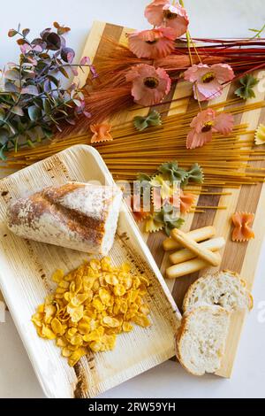 Lebensmittel für Zöliakie-Kranke zu vermeiden: Brot, Nudeln und Getreide. Das Konzept der Gluten-, Diät- und Weizenprodukte. Dekoriert mit getrockneten Blumen. Stockfoto