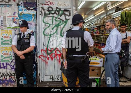 London, Großbritannien. September 2023. Ein Polizist spricht während der Demonstration mit einem Ladenbesitzer gegenüber Peckham Cosmetics auf der Rye Lane. Demonstratoren versammelten sich vor dem Peckham Hair and Cosmetics Shop über ein Video, das in den sozialen Medien zirkulierte. Das Video zeigt einen Streit zwischen einer Frau und dem männlichen Besitzer von Peckham Hair and Cosmetics, Sohail Sindho, 45, der während der Auseinandersetzung seine Hände um ihre Kehle zu legen scheint. Quelle: SOPA Images Limited/Alamy Live News Stockfoto