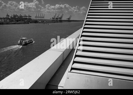 Hamburg, Deutschland - 17. Juni 2023: Elblandschaft mit Hafenkranen, Hafengebäude und Fähre in Schwarz-weiß Stockfoto