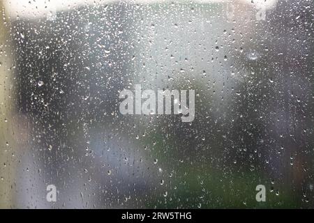 Wasser, Regentropfen auf der Fensterscheibe, Glas. Lichter der Stadt. Bokeh - abstrakter Hintergrund. Stockfoto