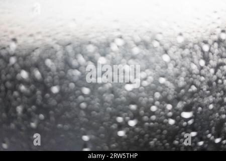 Wasser, Regentropfen auf der Fensterscheibe, Glas. Lichter der Stadt. Bokeh - abstrakter Hintergrund. Stockfoto