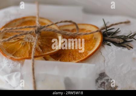 Weihnachtsstollen mit getrockneten Orangenfrüchten und Fichtenzweig. Neujahrsbacken. Ein süßes Geschenk. Traditioneller Weihnachtskuchen in Geschenkverpackung. Stockfoto