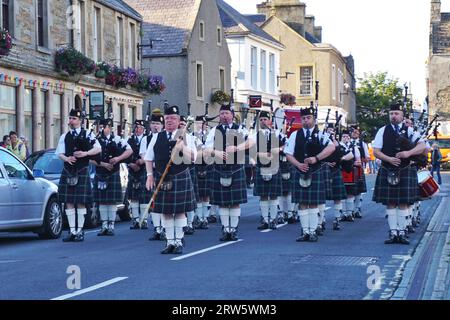 Die Mitglieder der Kirkwall City Pipe Band stehen mit ihrem Schlagzeug-Major vor der Tür, während sie auf der Hauptstraße von Kirkwall, Orkney Island, auftreten Stockfoto