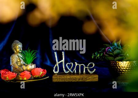 Buddha-Statue mit einer saftigen Pflanze, umgeben von saftigen Pflanzen, Wohnkultur, unscharfe Blätter vorne Stockfoto