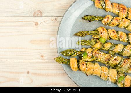Grüner Spargel, gebacken in Teig mit Pesto-Sauce auf einem rustikalen Holztisch. Leerzeichen kopieren. Stockfoto