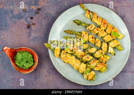 Vegetarischer grüner Spargel in Teig gebacken mit Basilikum-Pesto-Sauce. Stockfoto