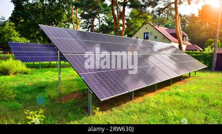 Solarpaneele mit großer Oberfläche. Photovoltaikpaneele stehen auf einer gepflasterten Oberfläche vor dem Hintergrund von Bäumen und Büschen. Stockfoto