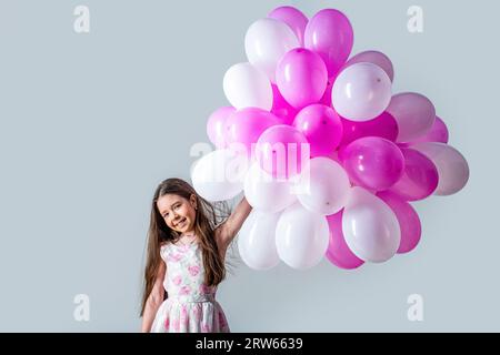 Kleines Mädchen, das Heliumballons hält. Kinder glückliche kleine Mädchen bunte Ballons. Porträt eines glücklichen Teenagers oder Jugendlichen. Kindergeburtstag Stockfoto