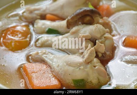 Gekochtes, geschmortes Hühnchen mit Karotte und Tomatenzwiebeln auf Pilzsuppe auf dem Teller Stockfoto