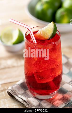 Kaltes Kirschgetränk mit Limettenspalten auf Holztisch Stockfoto