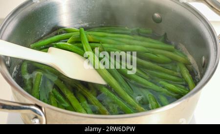 Nahaufnahme gekochte grüne Bohnen. Französische Bohnen, Haricots Verts, in einem Topf mit kochendem Wasser, Kochvorgang aus nächster Nähe, Rezept Stockfoto