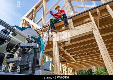 Professioneller kaukasischer Holzhaus Skelett Frame Contractor Arbeiter in seinen 40er Jahren auf dem House Top Level Stockfoto