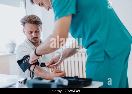 Erfahrener Arzt misst den Blutdruck und überprüft die Herzfrequenz des männlichen Patienten in der medizinischen Praxis für Diagnose und Behandlung. Stockfoto