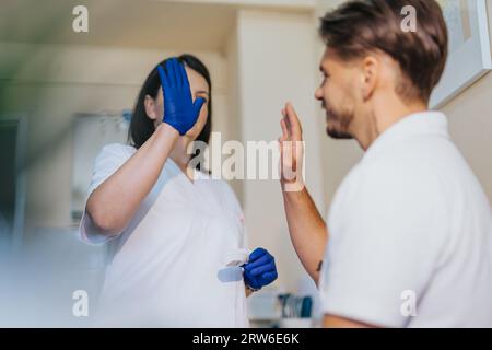 In einem Krankenhauszimmer überprüft ein medizinisches Fachpersonal Blutdruck und Blutzucker und führt eine Höruntersuchung mit einem Otoskop durch. Sie sammeln auch ein M Stockfoto