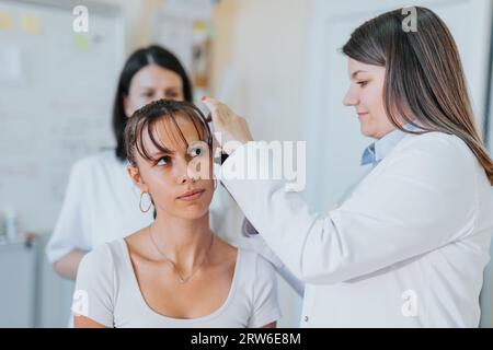 Eine erfahrene Ärztin untersucht in einer Klinik Sehvermögen, Hörvermögen und Hals eines jungen Patienten. Stockfoto
