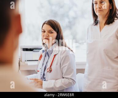 Eine Frau erhält eine gründliche medizinische Untersuchung und medizinische Unterstützung in einer Klinik, einschließlich einer Diskussion über gesundheitliche Probleme, Überprüfung des Blutdrucks und Stockfoto