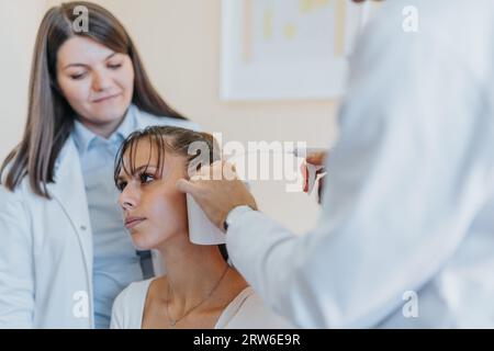 Erfahrener Arzt führt umfassende Untersuchungen an jungen Patienten in einer Klinik durch, um Sehkraft, Gehör und Hals für eine effektive Gesundheitsversorgung zu überprüfen Stockfoto