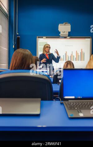 Erwachsenenprofessorin, die ihren Schülern die Präsentation im College-Klassenzimmer erklärt, E-Learning-Online-Schule Stockfoto