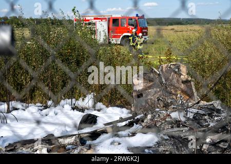 Bamberg, Deutschland. September 2023. Der Löschschaum der Feuerwehr breitet sich zwischen den Trümmerteilen eines Flugzeugs hinter einem Zaun aus. Auf dem Flugplatz Bamberg-Breitenau stürzte laut Polizei ein kleines Flugzeug beim Start ab. Quelle: Pia Bayer/dpa/Alamy Live News Stockfoto