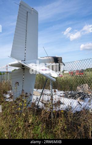 Bamberg, Deutschland. September 2023. Die Trümmer eines Flugzeugs hängen in einem Zaun, während Feuerwehrfahrzeuge am Einsatzort stehen. Auf dem Flugplatz Bamberg-Breitenau stürzte laut Polizei ein kleines Flugzeug beim Start ab. Quelle: Pia Bayer/dpa/Alamy Live News Stockfoto