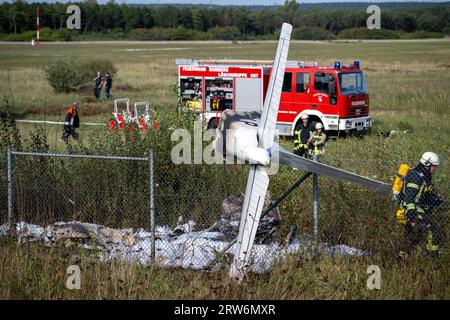 Bamberg, Deutschland. September 2023. Trümmer aus einem Flugzeug hängen in einem Zaun, während Feuerwehrmänner an der Absturzstelle stehen. Auf dem Flugplatz Bamberg-Breitenau stürzte laut Polizei ein kleines Flugzeug beim Start ab. Quelle: Pia Bayer/dpa/Alamy Live News Stockfoto