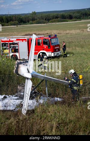 Bamberg, Deutschland. September 2023. Feuerwehrleute untersuchen die Trümmer eines Flugzeugs, das in einem Zaun an der Absturzstelle hängt. Auf dem Flugplatz Bamberg-Breitenau stürzte laut Polizei ein kleines Flugzeug beim Start ab. Quelle: Pia Bayer/dpa/Alamy Live News Stockfoto