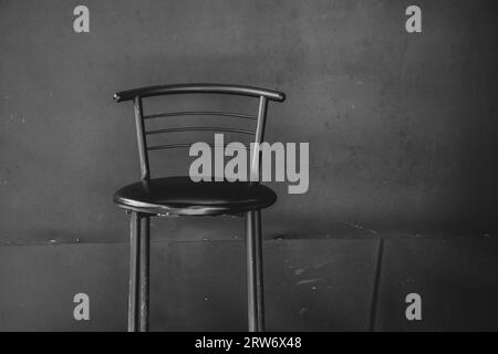Ein alter schäbiger Stuhl steht vor dem Hintergrund einer schwarzen Wand aus Nahaufnahme, Möbel und Design Stockfoto