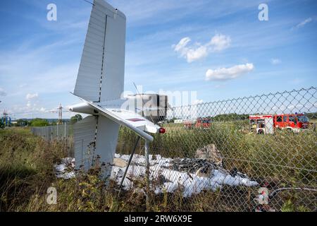 Bamberg, Deutschland. September 2023. Die Trümmer eines Flugzeugs hängen in einem Zaun, während Feuerwehrfahrzeuge am Einsatzort stehen. Auf dem Flugplatz Bamberg-Breitenau stürzte laut Polizei ein kleines Flugzeug beim Start ab. Quelle: Pia Bayer/dpa/Alamy Live News Stockfoto