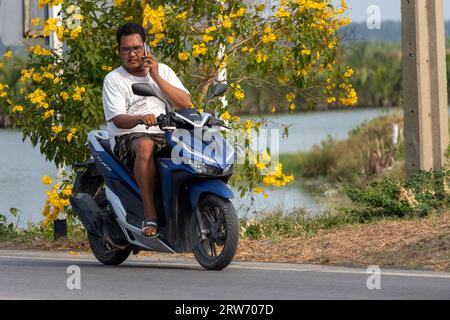 SAMUT PRAKAN, THAILAND, MAR 09 2023, Ein Mann fährt Ein Motorrad und ruft über ein Mobiltelefon an Stockfoto