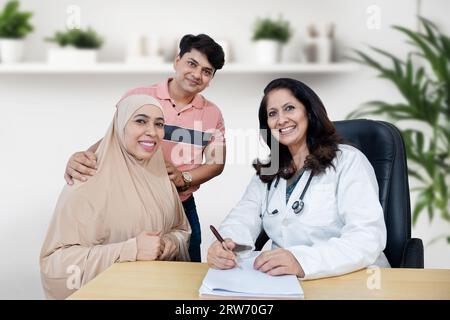 Porträt einer indischen Ärztin, die junge muslimische Ehepaare in der Kinderwunschklinik über IVF oder IUI berät. Schwangerschaftsplanung. Smi Stockfoto