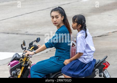 SAMUT PRAKAN, THAILAND, Juni 2023, Eine Frau reitet mit einem Mädchen in einer Schuluniform ein Motorrad Stockfoto