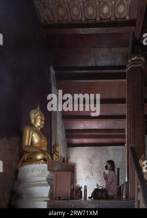 Phetchaburi, Thailand - 14. Mai 2022 : Junge Frau, die sitzt, zollt Phra Phuttha Chinnarat in der Kapelle des Wat yai Suwannaram-Tempels Respekt. Anbetung p Stockfoto