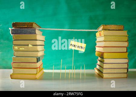 Bekämpfen Sie Fake News, Bildung, Lernen, Wissen, zurück zur Schule, Medienkompetenz mit Slackline und Stapeln von Büchern, kostenlose Kopien Stockfoto