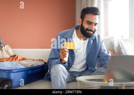 Touristentyp aus dem Nahen Osten, der mit einem Laptop zu Hause bezahlt Stockfoto