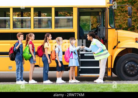 Schwarze Lehrerin, die Schülern in der Nähe des Schulbusses Fauststöße gibt Stockfoto