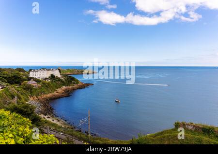 Blick auf Killiney Bay an sonnigen Sommertagen entlang der Küste. Luxuswohnungen auf der 'Sorrento Terrace', Boote und 'DART'-Bahn im Vordergrund. Dublin, Irland Stockfoto