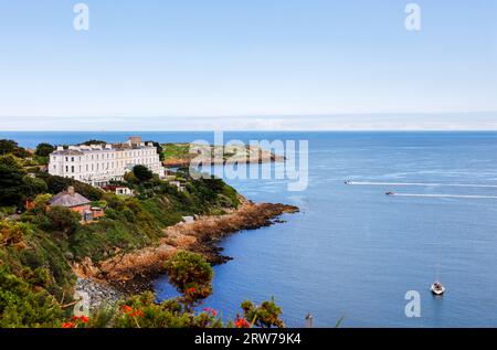 Blick auf 'Sorrento Terrace' Luxushäuser entlang der Küste mit Blick auf Killiney Bay. Menschen, die an sonnigen Sommertagen in Schnellbooten segeln. Dublin, Irland Stockfoto